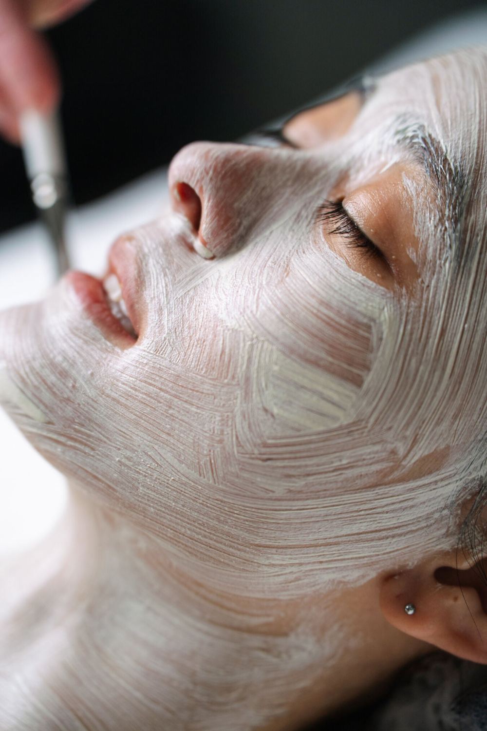 Person receiving a facial treatment with a white mask on their face at Ilumae Skin Bar